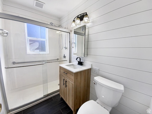 full bathroom featuring visible vents, toilet, wood tiled floor, a shower stall, and vanity