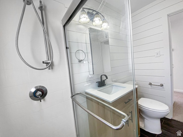 full bath with toilet, a tile shower, vanity, and wood finished floors