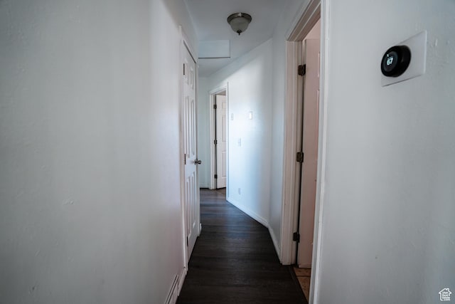 corridor with dark wood-type flooring and baseboards