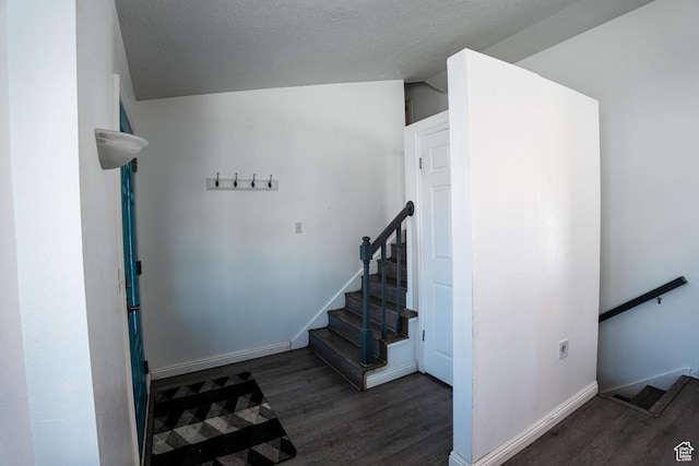 stairs featuring baseboards, vaulted ceiling, wood finished floors, and a textured ceiling