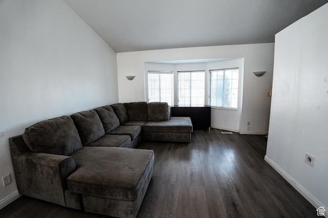 living area featuring dark wood-style flooring, baseboards, and vaulted ceiling