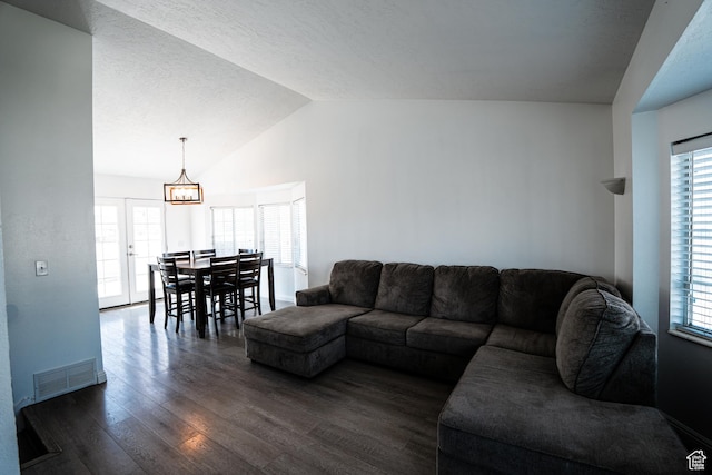 living area featuring dark wood-style flooring, vaulted ceiling, visible vents, and a wealth of natural light