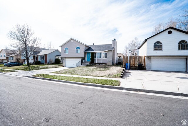 4129 W Misty Dr S, Taylorsville, UT 84129 - split level home featuring an attached garage, concrete driveway, entry steps, and a chimney
