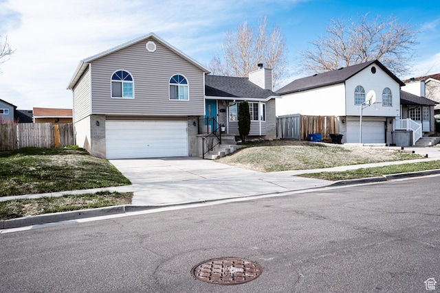 4129 W Misty Dr S, Taylorsville, UT 84129 - tri-level home featuring a garage, driveway, and a chimney