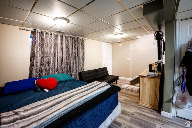bedroom featuring wood finished floors, baseboards, and a drop ceiling
