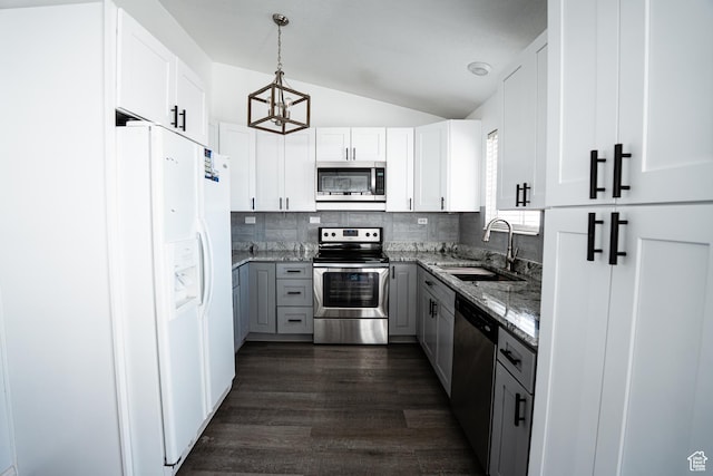kitchen with a sink, appliances with stainless steel finishes, gray cabinets, backsplash, and light stone counters
