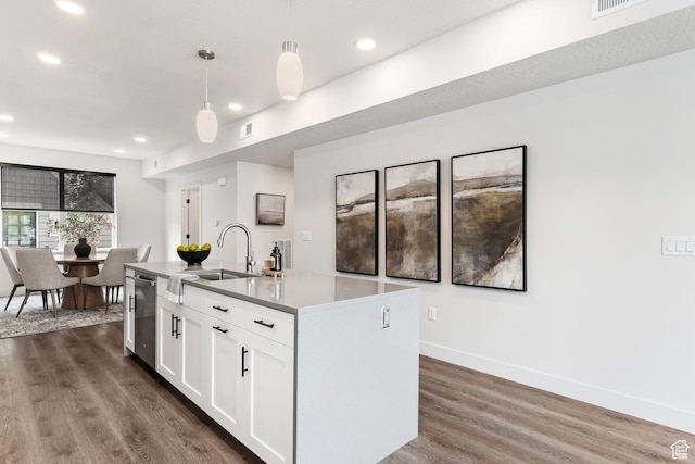kitchen featuring stainless steel dishwasher, dark wood-type flooring, white cabinets, a sink, and a center island with sink