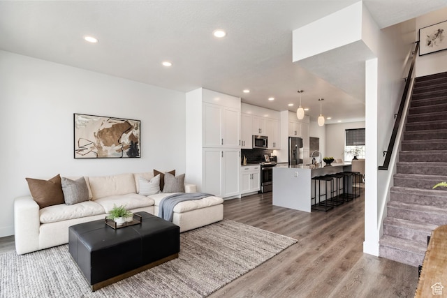 living area featuring wood finished floors, recessed lighting, and stairway