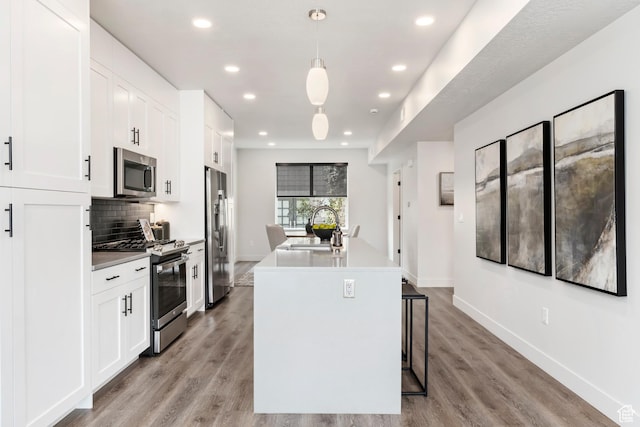 kitchen featuring white cabinets, a sink, an island with sink, stainless steel appliances, and backsplash