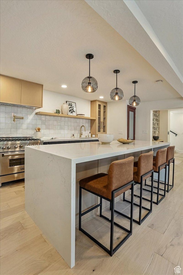 5290 E Emigration Canyon Rd, Salt Lake City, UT 84108 - kitchen featuring light wood-type flooring, a large island, decorative backsplash, and stainless steel range