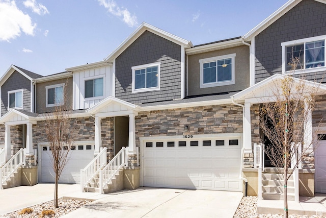townhome / multi-family property with driveway, stone siding, and a garage