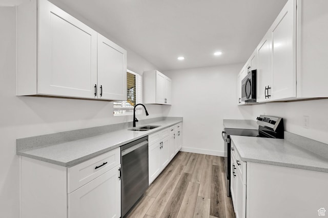 1289 E 31st St S, Ogden, UT 84403 - kitchen with light wood-style floors, appliances with stainless steel finishes, a sink, and white cabinets