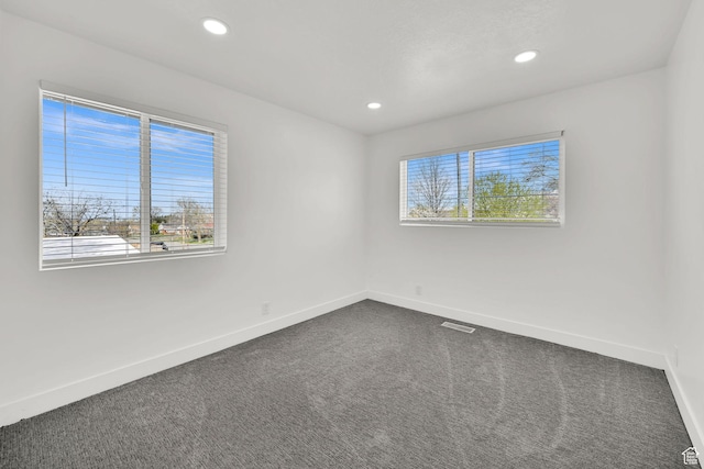 1289 E 31st St S, Ogden, UT 84403 - empty room featuring visible vents, baseboards, dark colored carpet, and a healthy amount of sunlight