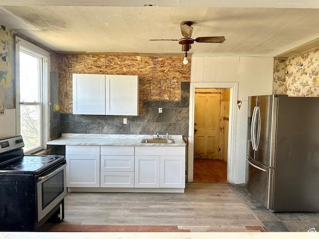 kitchen with white cabinets, light countertops, a ceiling fan, light wood finished floors, and stainless steel appliances