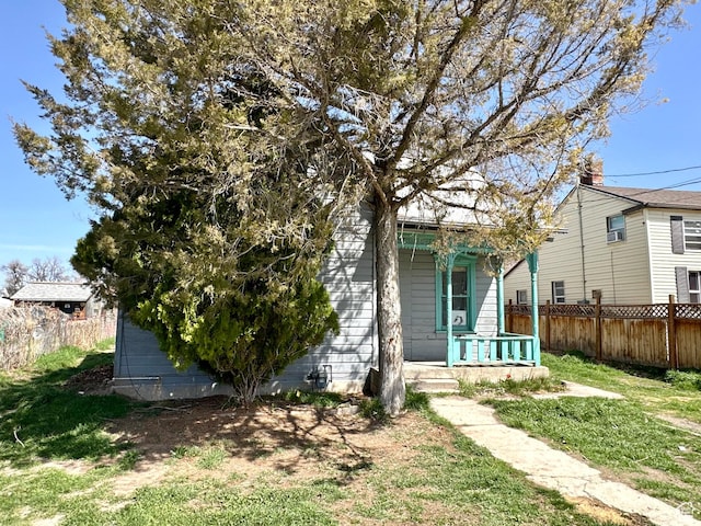 rear view of house with a yard, a porch, and fence