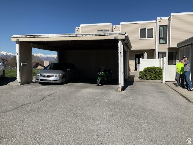 view of parking with a mountain view and fence