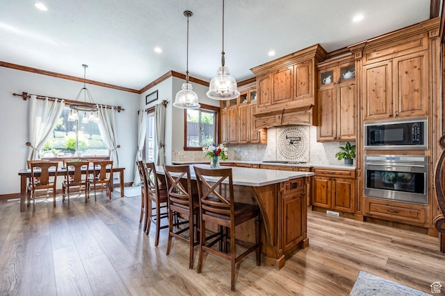 kitchen featuring light wood-type flooring, light countertops, backsplash, brown cabinets, and stainless steel appliances
