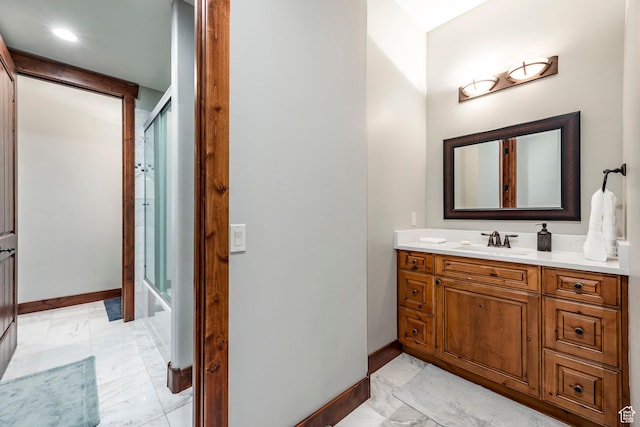 bathroom featuring shower / bath combination with glass door, vanity, and baseboards