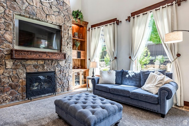 living area featuring plenty of natural light and a stone fireplace