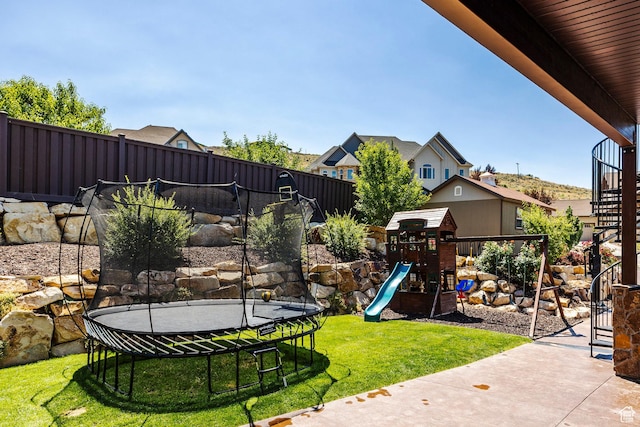 view of yard with a trampoline, fence, and a playground