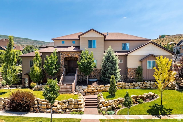 craftsman inspired home with board and batten siding, stone siding, a front lawn, and stairs