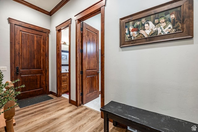 entrance foyer with ornamental molding and light wood-style floors