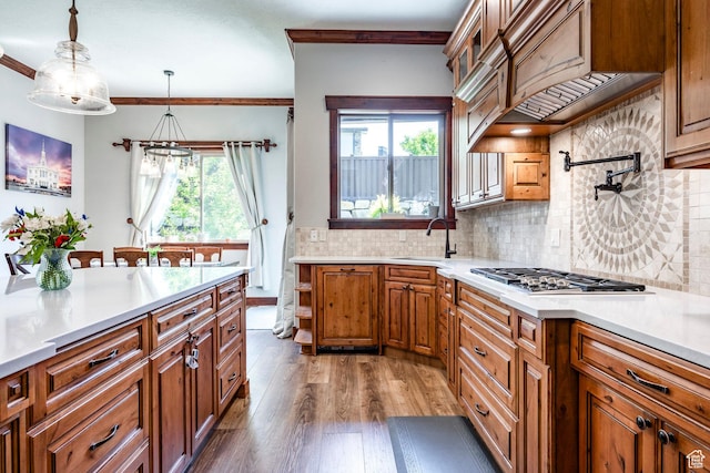 kitchen with light countertops, wood finished floors, a sink, and ornamental molding