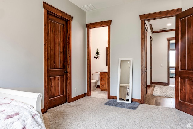 carpeted bedroom with visible vents, baseboards, and connected bathroom