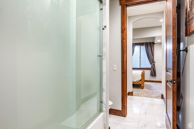 ensuite bathroom with baseboards, ensuite bathroom, toilet, a shower with shower door, and marble finish floor