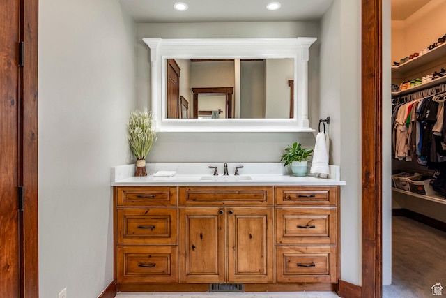 bathroom featuring visible vents, baseboards, a spacious closet, recessed lighting, and vanity