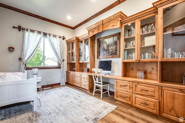 office with built in desk, ornamental molding, light wood-style flooring, and baseboards