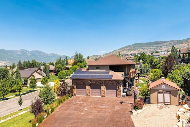 view of front of house featuring concrete driveway, an outdoor structure, a mountain view, solar panels, and a garage