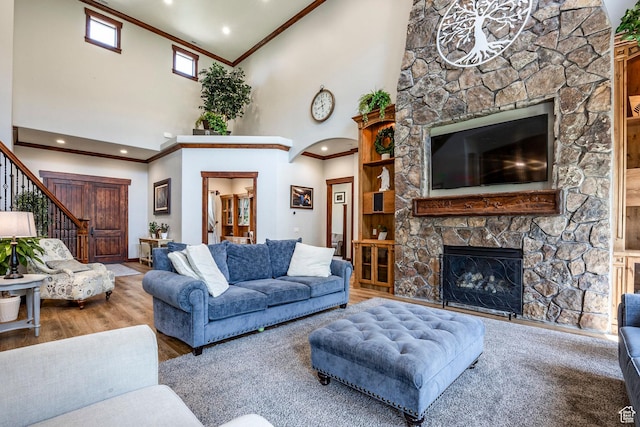 living room with a fireplace, stairway, a high ceiling, arched walkways, and wood finished floors