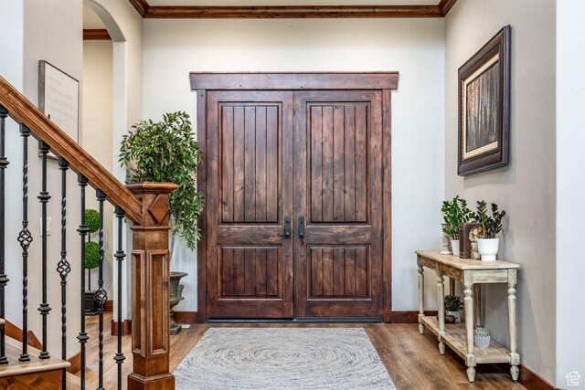 foyer entrance featuring arched walkways, crown molding, dark wood-style floors, and stairway