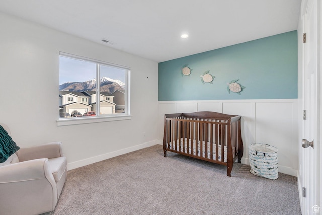 bedroom featuring carpet, a nursery area, visible vents, recessed lighting, and wainscoting