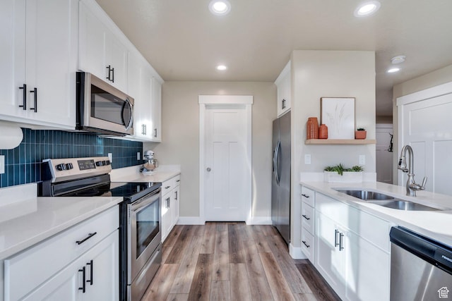 kitchen with tasteful backsplash, open shelves, white cabinets, appliances with stainless steel finishes, and a sink
