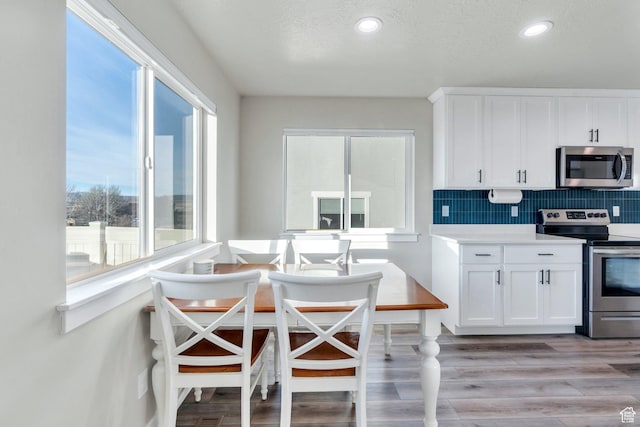 kitchen featuring light countertops, appliances with stainless steel finishes, white cabinetry, backsplash, and light wood-style flooring