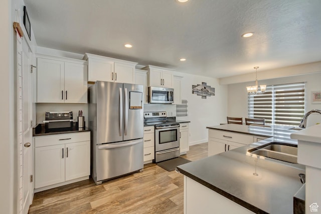 483 S Fox Chase Ln, Saratoga Springs, UT 84045 - kitchen with white cabinets, a sink, dark countertops, stainless steel appliances, and light wood finished floors