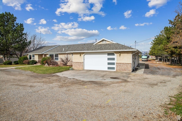 view of front facade featuring a front yard, a garage, stucco siding, brick siding, and driveway