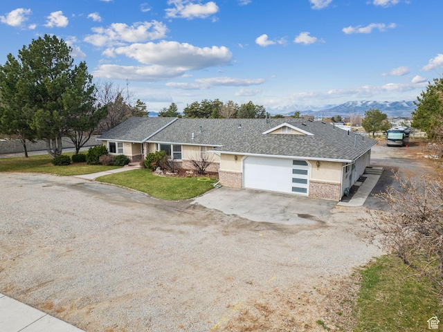 ranch-style house featuring roof with shingles, stucco siding, a mountain view, driveway, and a garage