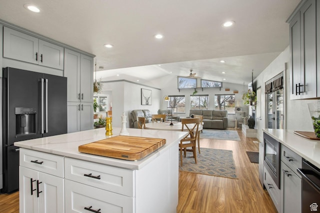 kitchen with light wood-style floors, high end black refrigerator, vaulted ceiling, open floor plan, and gray cabinetry