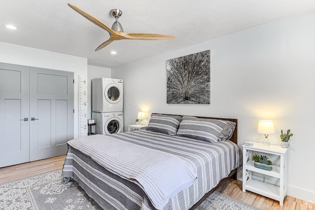 bedroom featuring ceiling fan, stacked washer and clothes dryer, light wood-style floors, a textured ceiling, and recessed lighting