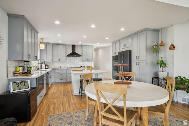 kitchen featuring a sink, gray cabinetry, fridge, and wall chimney exhaust hood