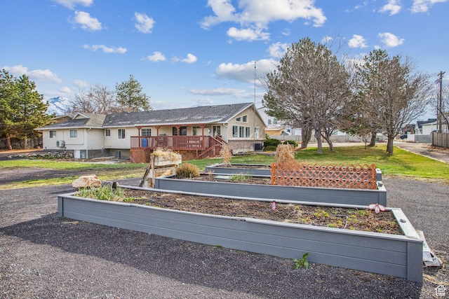 exterior space with a front yard, a garden, and a wooden deck