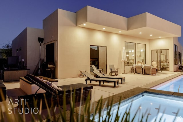 rear view of house with an outdoor living space, an outdoor pool, a patio area, and stucco siding