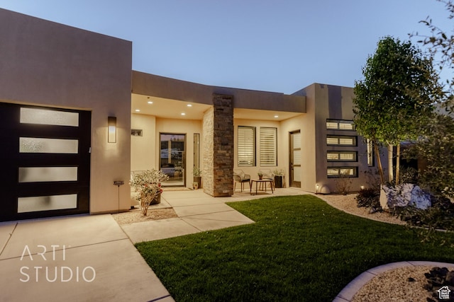 entrance to property with a yard, a patio area, and stucco siding