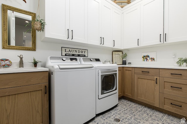 laundry area with washing machine and dryer, a sink, and cabinet space