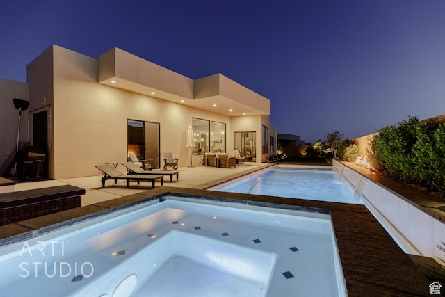 pool at twilight with a patio area, an in ground hot tub, and an outdoor pool