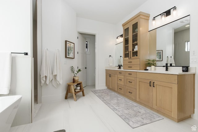 bathroom featuring a sink, baseboards, double vanity, and a soaking tub