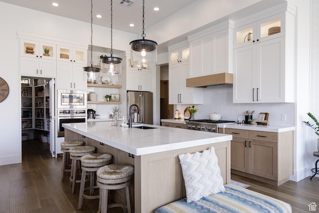 kitchen with tasteful backsplash, a sink, a kitchen island with sink, stainless steel appliances, and a breakfast bar area